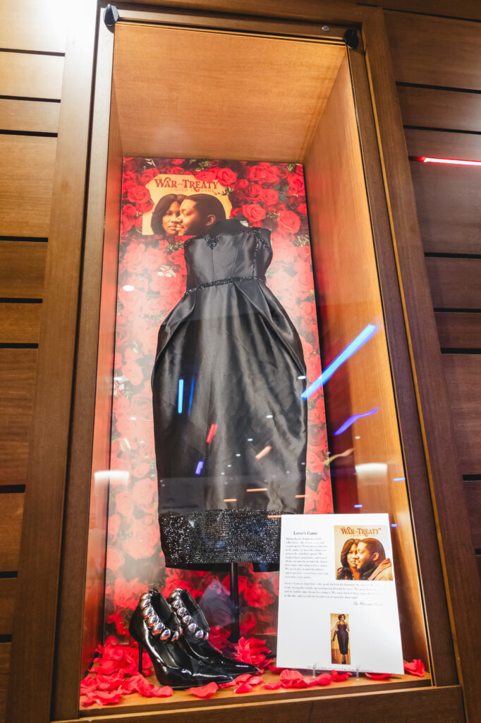 Black dress hanging in glass case for War and Treaty lobby case exhibition