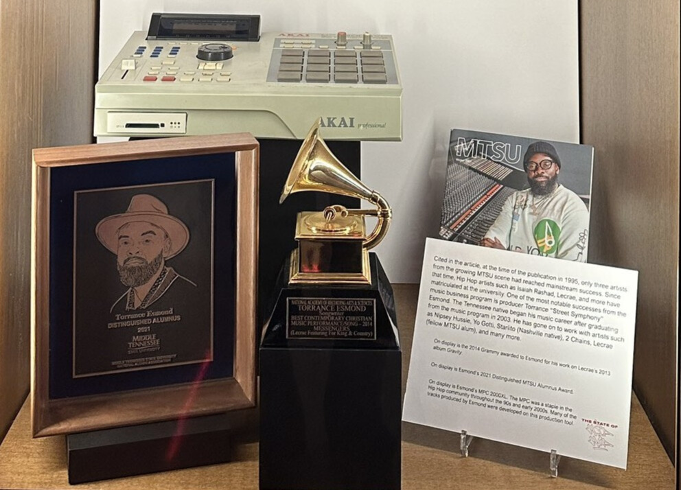 close up of exhibition items in glass case: awards and recognition and beat making machine