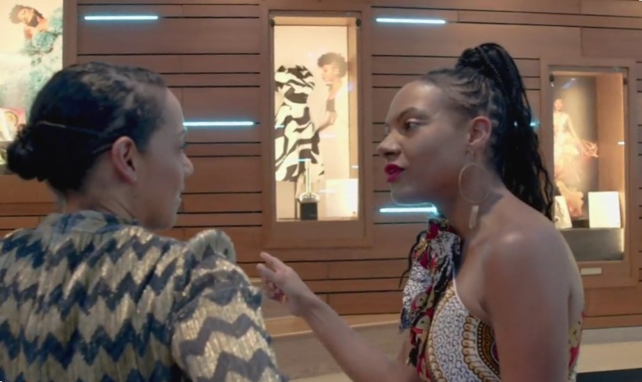 Artist speaking to moderator in front of exhibition case