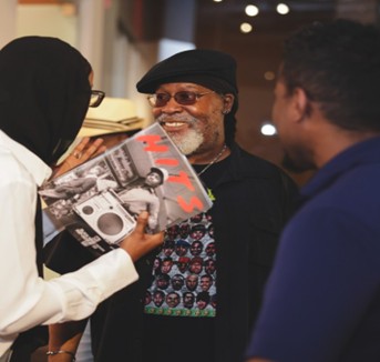 artist smiling with visitors in gallery