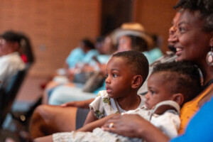 two small children sitting with mother watching puppet show in NMAAM theatre