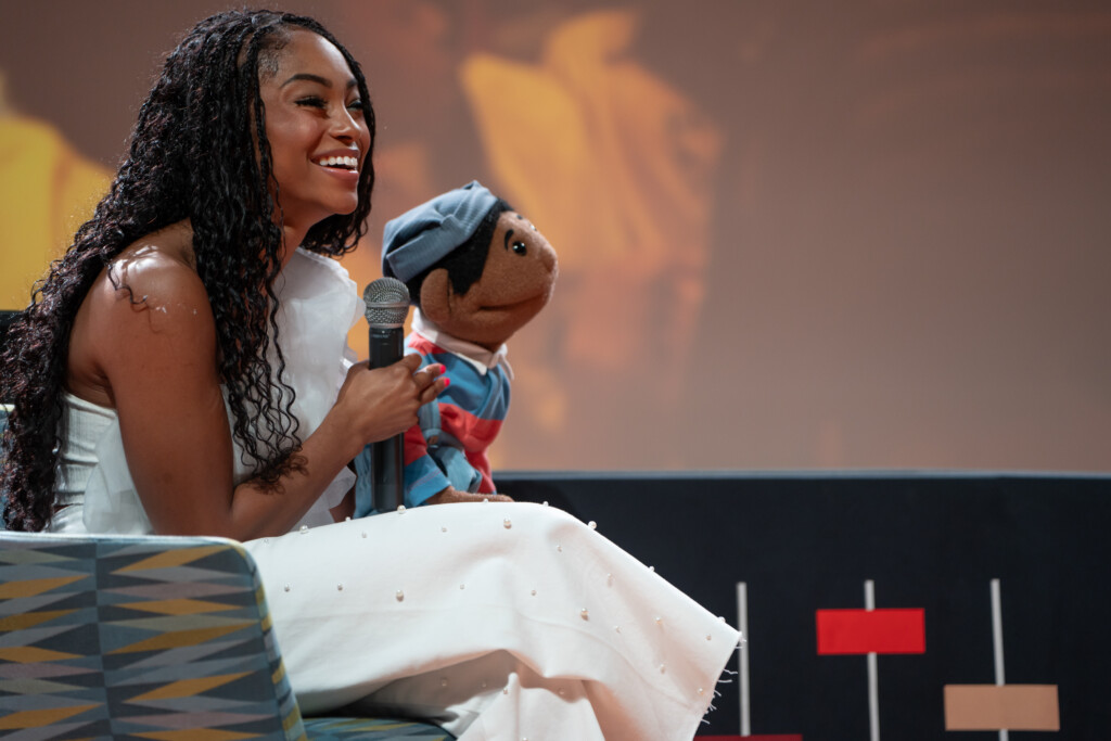 Megan Piphus on stage holding microphone and puppet during Q&A