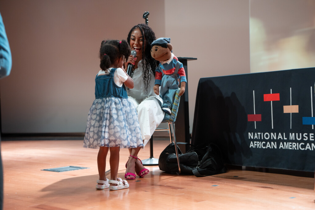 child on stage with Megan Piphus and puppet