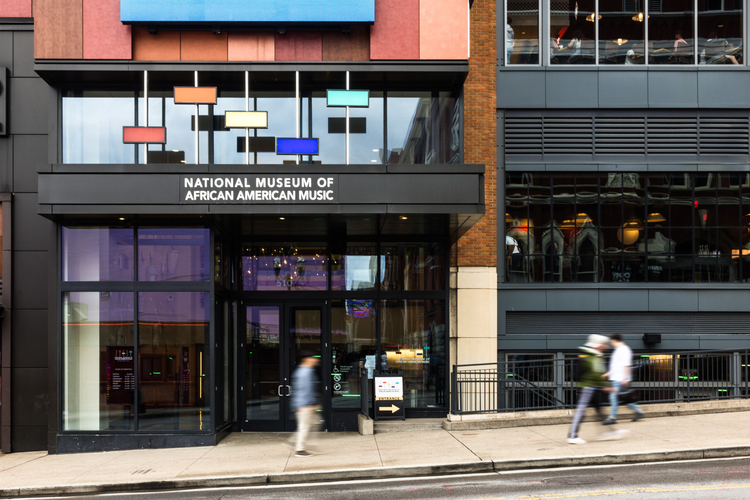 Exterior facade of NMAAM building on 5th Ave with three people walking on sidewalk